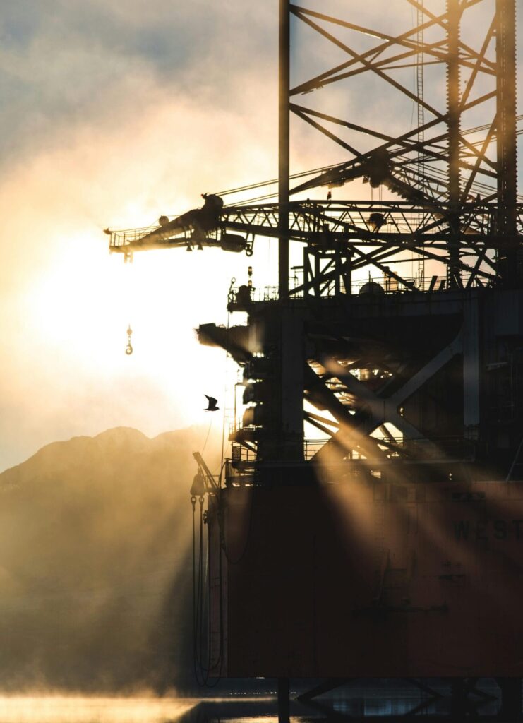 Dramatic silhouette of industrial machinery against a foggy morning sunrise, capturing the essence of heavy industry.