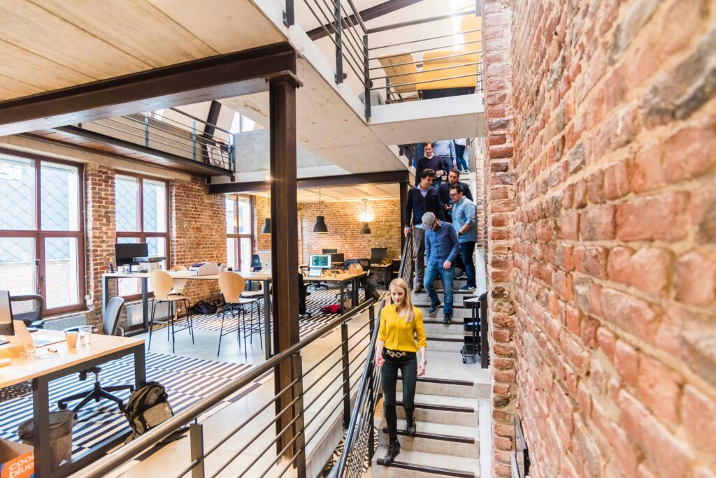 Open-concept office with brick walls, multi-level layout, and team members working together.